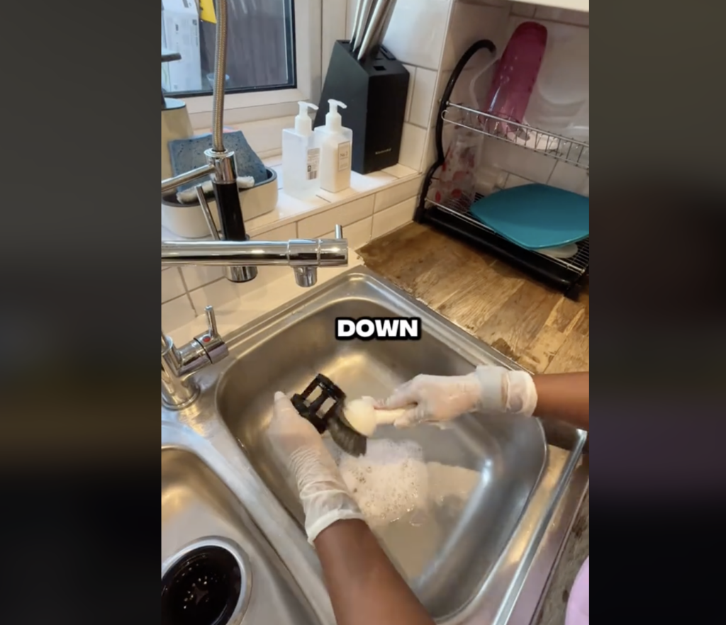 woman washing washing machine filter in the sink